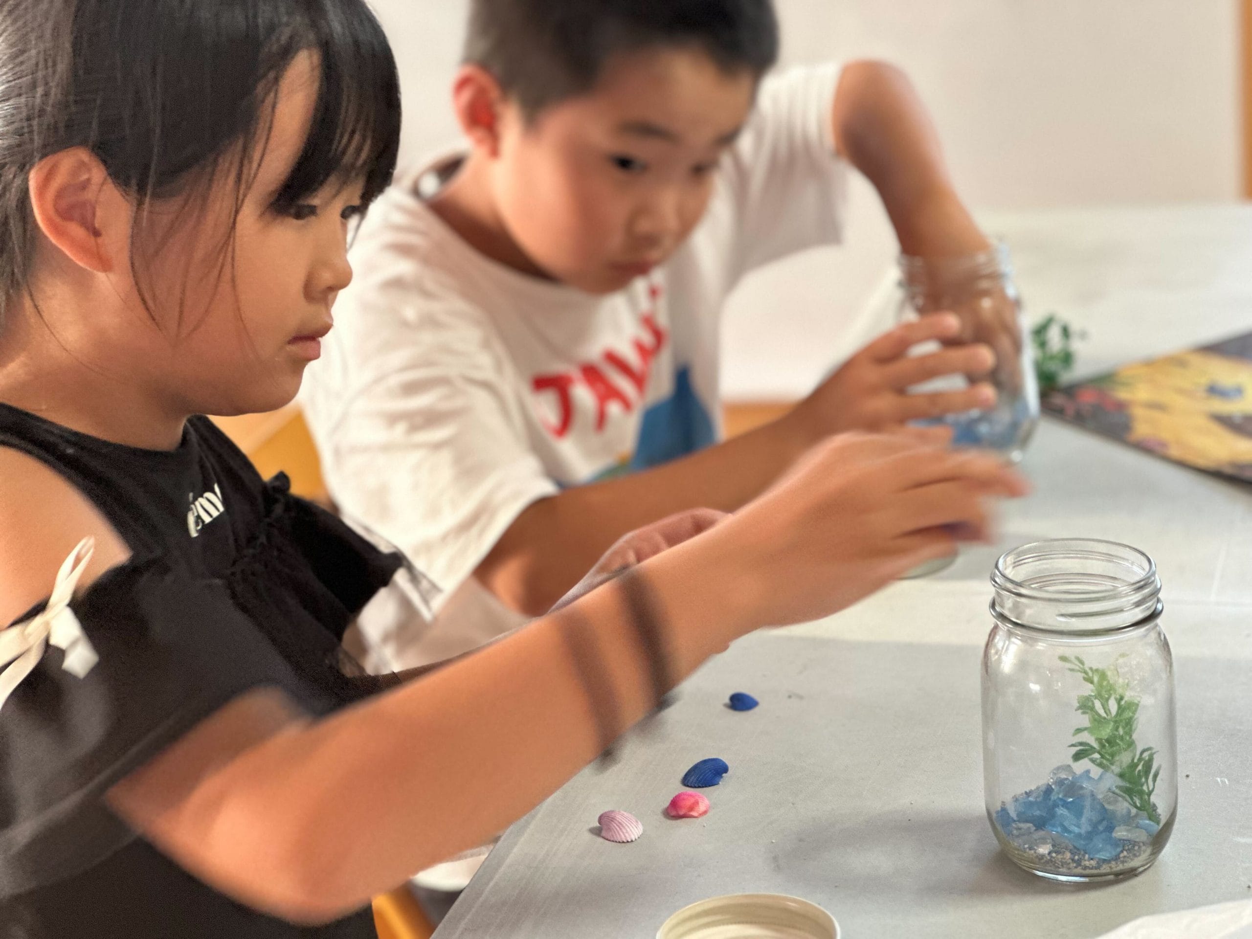 Children creating miniature terrariums during a hands-on special club activity at The Clubhouse after school program in eastern Nagoya.